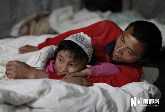 深夜，芦山县人民医院内的帐篷医务室，10岁的吴玲荣和爸爸躺在病床上睡觉。她在地震中头部被掉落的天花撞伤。